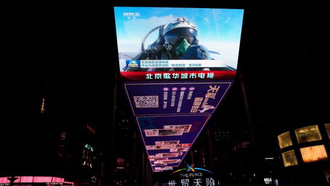 An outdoor screen depicts a Chinese fighter jet pilot giving a thumbs up in the recently concluded Joint Sword exercise around Taiwan during the evening news broadcast in Beijing, Monday, April 10, 2023. China's military declared Monday it is "ready to fight" after completing three days of large-scale combat exercises around Taiwan that simulated sealing off the island in response to the Taiwanese president's trip to the U.S. last week. (AP Photo/Ng Han Guan)