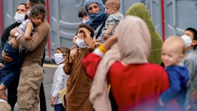 People evacuated from Afghanistan step off a bus as they arrive at a processing centre