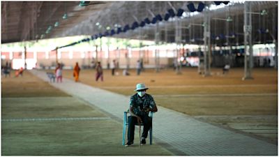 A volunteer keeps guard as workers prepare a facility that can accommodate more than ten thousand COVID-19 patients.