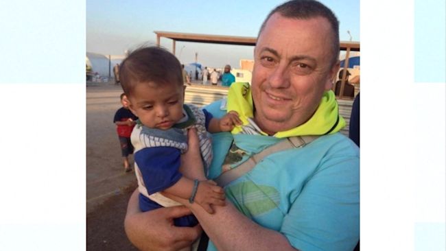 Alan Henning with a young child as he delivered aid