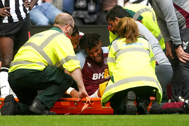 Mings surrounded by first aiders on the pitch.