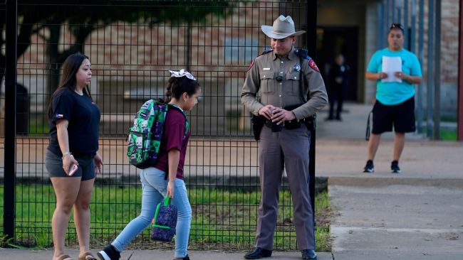 A student walks past an armed law enforcement officer on their return to school in Uvalde.