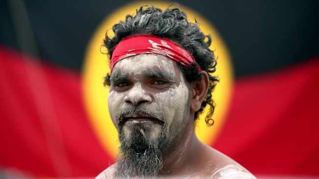 FILE - Stedman Sailor stands in front of the Aboriginal Australian Flag as he arrives with other members of the Aboriginal community to take part in a smoking ceremony as part of Australia Day celebrations in Sydney, Jan. 26, 2018. Australia’s House of Representatives voted overwhelming on Wednesday, May 31, 2023 in favor of holding a referendum this year on creating a so-called Indigenous Voice to Parliament, an advocate that promises the nation’s most disadvantaged ethnic minority more say on policies that effect their lives. (AP Photo/Rick Rycroft, File)