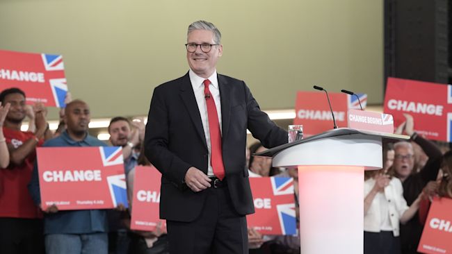 A smiling Starmer surrounded by people holding boards saying "change".