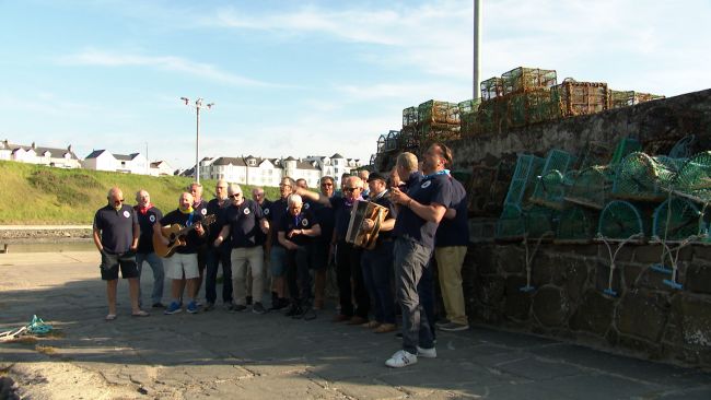 The Causeway Shantymen performing on the pier at Portballintrae harbour in Co. Antrim.