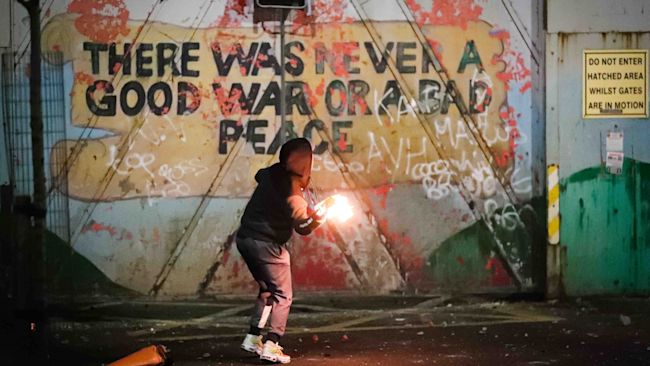 A mural on the peace wall at Lanark Way in west Belfast provides a poignant backdrop as youths hurl petrol bombs during disorder.