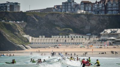 Surfers play in the waves during the hot sunshine on Great Western beach in Newquay, Cornwall in June 2019.