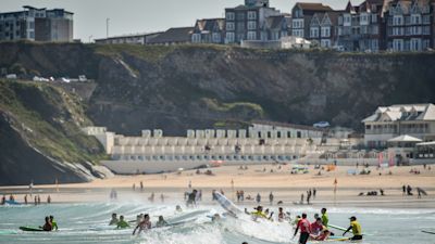 Surfers play in the waves during the hot sunshine on Great Western beach in Newquay, Cornwall in June 2019.