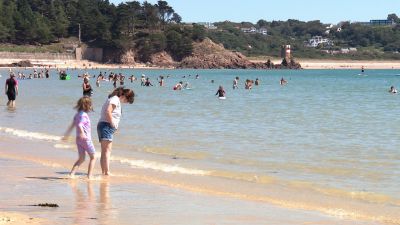 People on the beach and in the water at St Brelade's Bay Jersey.