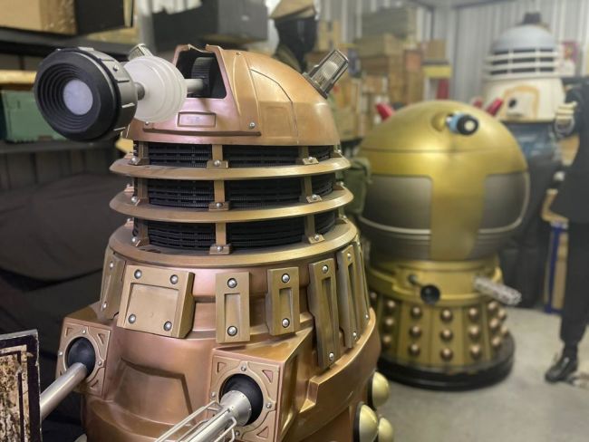 Three Daleks stand in storage facing towards the camera 