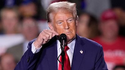 Former President Donald Trump taps the microphone as the audio goes out during a campaign event. AP