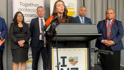 New Zealand Prime Minister Jacinda Ardern delivers a speech, flanked by lawmakers, Thursday, Aug. 12, 2021, in Wellington, New Zealand. Ardern announced plans to begin a cautious reopening of New Zealand's borders to international travelers from early next year.(AP Photo/Nick Perry)
