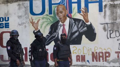 Police stand near a mural featuring Haitian President Jovenel Moise, near the leader's residence where he was killed