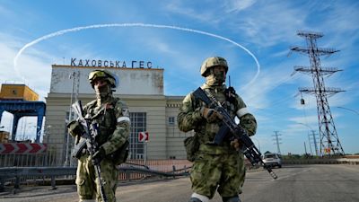 FILE - Russian troops guard an entrance of the Kakhovka Hydroelectric Station, a run-of-river power plant on the Dnieper River in Kherson region, south Ukraine, on May 20, 2022. According to Russian state TV, the future of the Ukrainian regions occupied by Moscow's forces is all but decided: Referendums on becoming part of Russia will soon take place there, and the joyful residents who were abandoned by Kyiv will be able to prosper in peace. In reality, the Kremlin appears to be in no rush to seal the deal on Ukraine's southern regions of Kherson and Zaporizhzhia and the eastern provinces of Donetsk and Luhansk. (AP Photo)