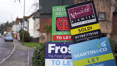 A number of for sale signs outside a row of houses in Surrey.