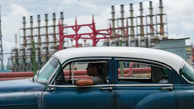 A person drives a classic American car past a floating generator that has not been producing electricity for days in Havana. AP