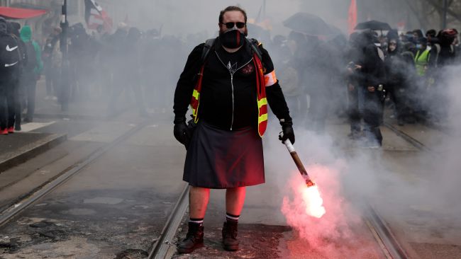 A demonstrator holds a flare during a protest Thursday, April 6, 2023 in Nantes, western France. 