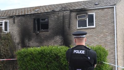 A police officer outside the fire-ravaged home on Staniforth Road in Suffolk where an 18-year-old man was killed.
