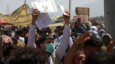 Hundreds of people gather, some holding documents, near an evacuation control checkpoint on the perimeter of the Hamid Karzai International Airport, in Kabul, Afghanistan, Thursday, Aug. 26, 2021. Western nations warned Thursday of a possible attack on Kabul's airport, where thousands have flocked as they try to flee Taliban-controlled Afghanistan in the waning days of a massive airlift. Britain said an attack could come within hours. (AP Photo/Wali Sabawoon)
