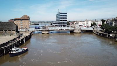 A view of the Haven Bridge looking at it side on from a drone hovering above the river. A boat is moored on the quay to the left