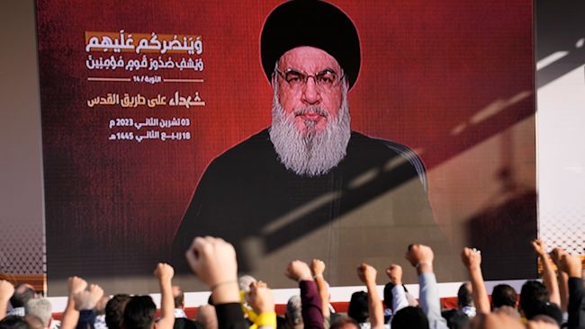 Supporters of Hezbollah raise their fists as the group's leader, Hassan Nasrallah, delivers a speech via video link.