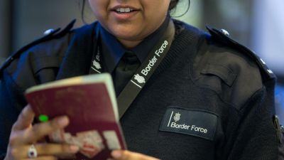 A Border Force official checks a passport.