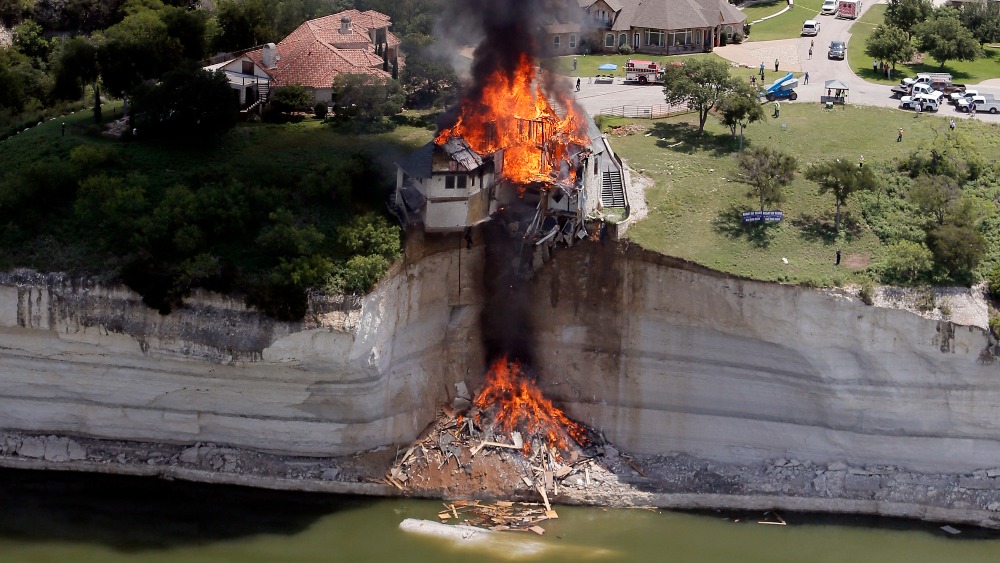 House teetering on edge of cliff is burnt down to solve problem | ITV News