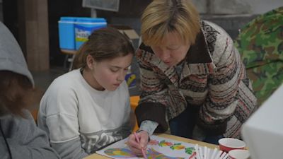 A teacher delivers an art lesson to a group of schoolchildren sheltering underground.