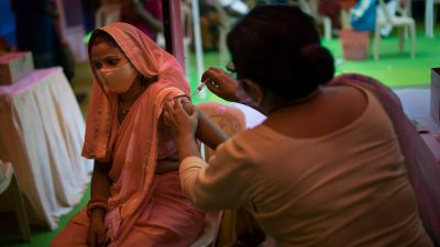 A health worker inoculates a woman during a vaccination drive against COVID-19 in New Delhi, India