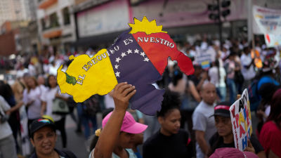 A woman holds a sign of the Venezuelan map with the Essequibo territory included during a rally in Caracas.