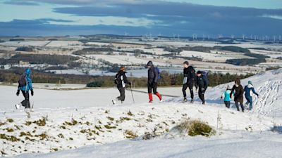 Hikers at Limestone Corner walk along a snow-covered Hadrian's Wall near Hexham, Northumberland.