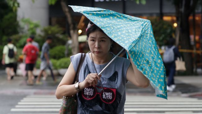 A woman struggles with her umbrella against gusts of wind generated by Typhoon Haikui in Taipei, Taiwan.