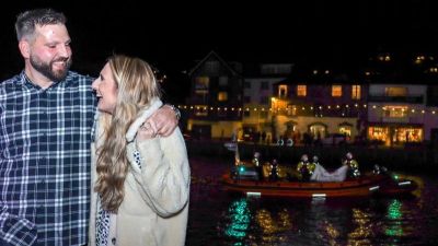 Aaron Rix and Katie Fisher with their marriage proposal lifeboat behind