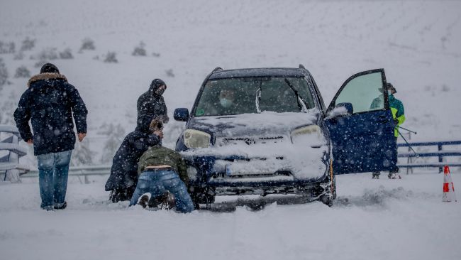 People put snow-chains on a car wheels during heavy snowfall in Rivas Vaciamadrid, Spain