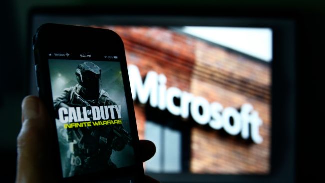 FILE - An image from Activision's Call of Duty is shown on a smartphone near a photograph of the Microsoft logo in this photo taken in New York, June 15, 2023. Microsoft’s purchase of video game maker Activision Blizzard won final approval Friday, Oct. 13, from Britain’s competition watchdog, reversing its earlier decision to block the $69 billion deal and removing a last obstacle for one of the largest tech transactions in history. (AP Photo/Peter Morgan, File)