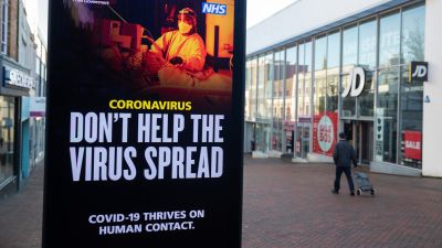 A person passes a 'Don't help the virus spread' government coronavirus sign on Commercial road in Bournemouth.