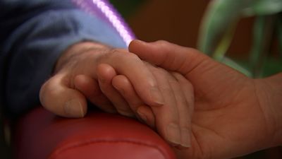 A person comforting somebodies hand.