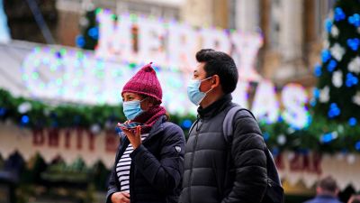 People wearing masks in Cardiff in front of Christmas sign