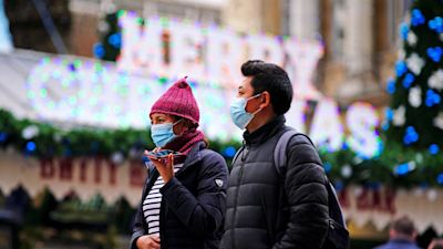 People wearing masks in Cardiff in front of Christmas sign