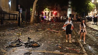 England fans walk through the litter strewn on the ground in Trafalgar Square, London, after Italy defeat