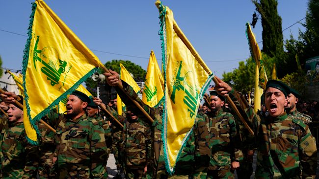 Hezbollah fighters raise their group's flag and shout slogans.