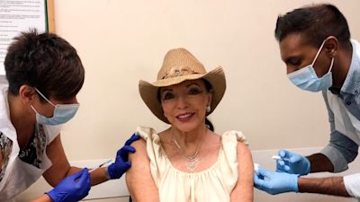 Handout photo issued by Percy Gibson of Dame Joan Collins receiving her coronavirus and flu jabs simultaneously. Issue date: Monday September 20, 2021.