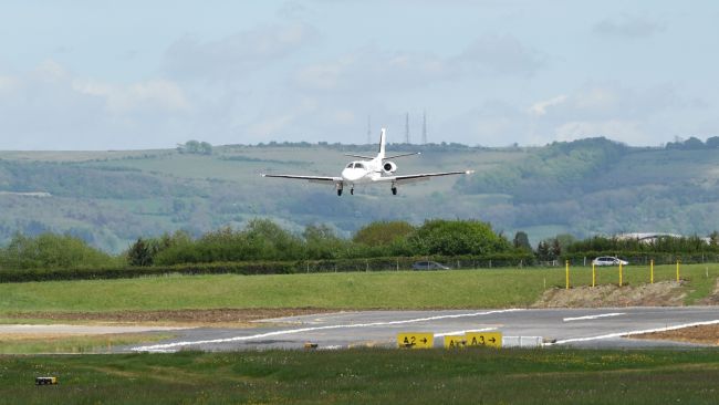 A photograph of a plane landing at Gloucestershire Airport.