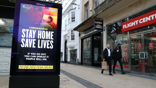 People walk past a 'Stay Home Save Lives' sign on Broadmead in Bristol during England's third national 