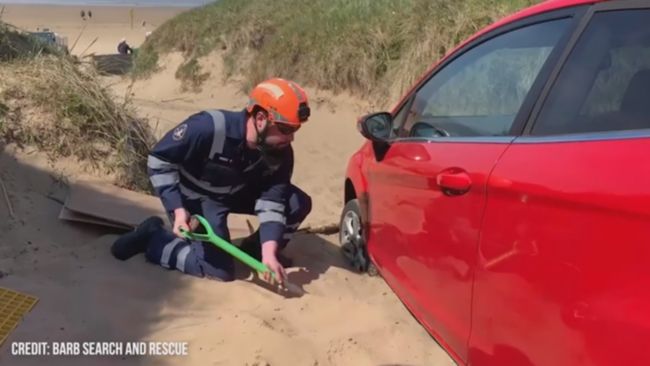 BARB Search and Rescue teams used spades to shovel sand away from the tyres of the trapped vehicle