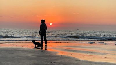 Cromer Sunrise in Norfolk with dog walker