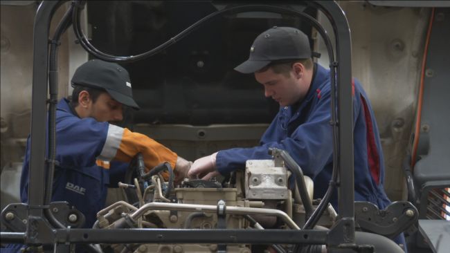 Two mechanics work on the engine of a HGV at a City of Bristol College training centre