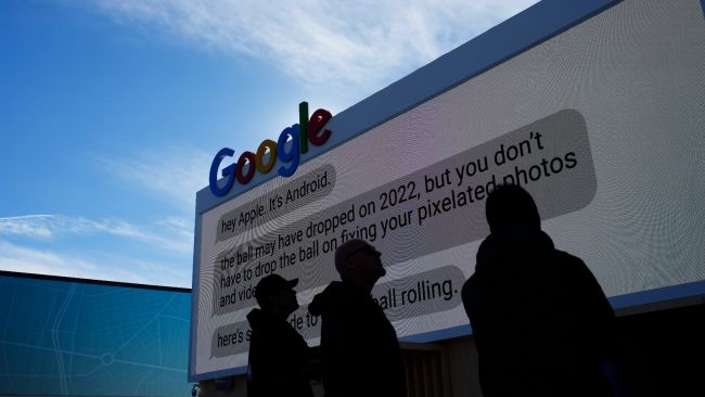 A group of people look at an advertising sign for Google.