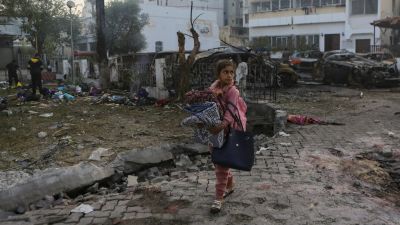 A girl carries blankets as she walks past the site of a deadly explosion at al-Ahli Hospital in Gaza City, Wednesday, Oct. 18, 2023. (AP Photo/Abed Khaled)


