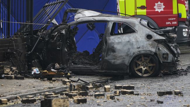The burnt out shell of a car at the scene on the Great Western Road, Notting Hill, west London, where three people have died after the vehicle collided with a residential block. Picture date: Tuesday September 14, 2021.
